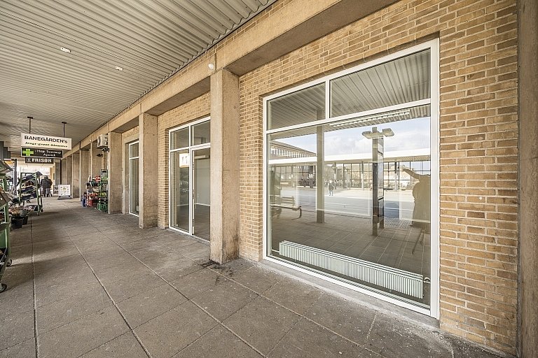 Facaden af et tomt lokale og apotek og frisør på Banestrøget 7 i Høje-Taastrup